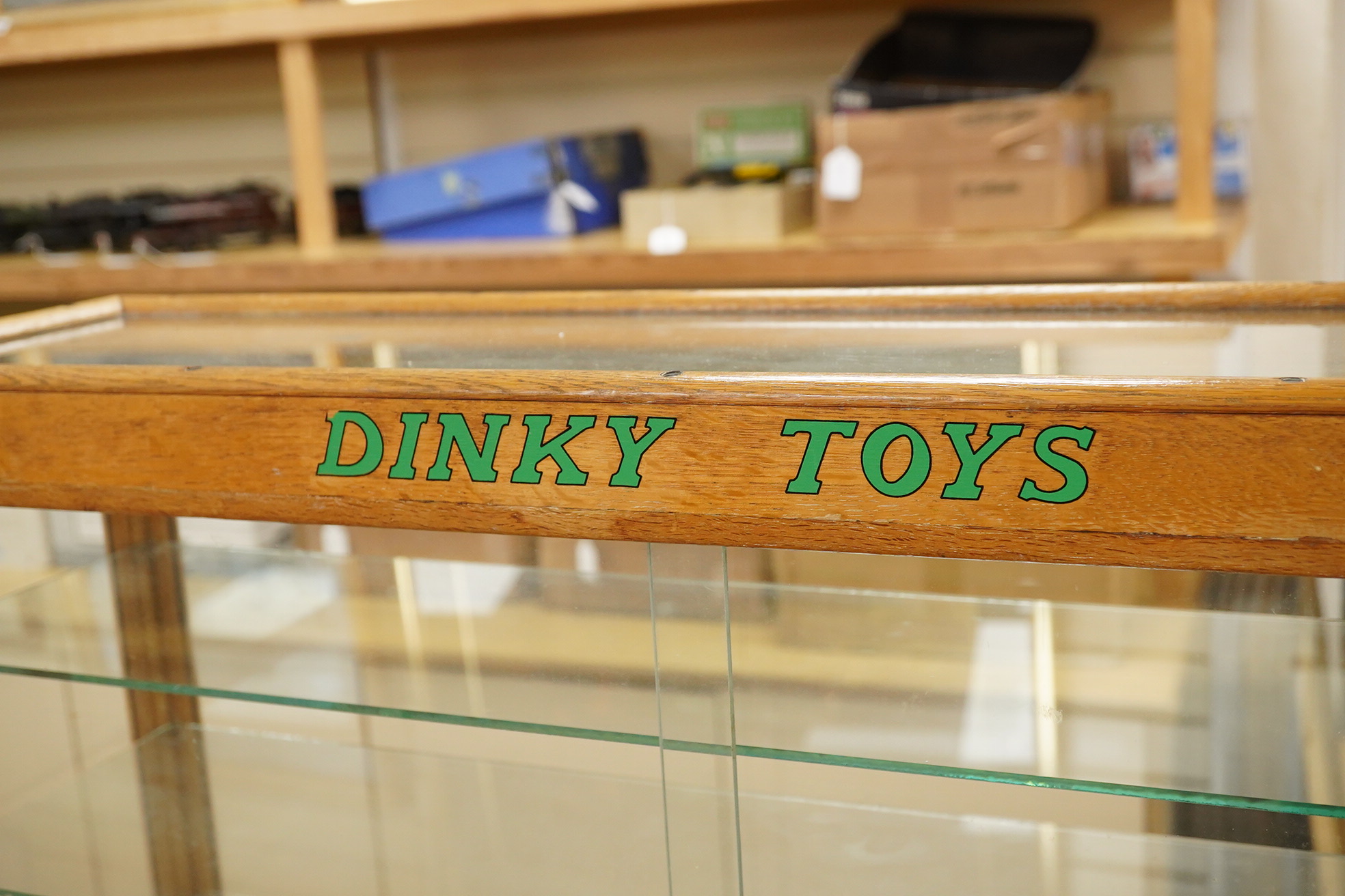 A Dinky Toys glazed oak shop counter retail display cabinet, this is the more scarce ‘front loading’ version of this cabinet, with ‘Dinky Toys’ in green to the top bar, height 61cm, width 81cm, depth 23cm